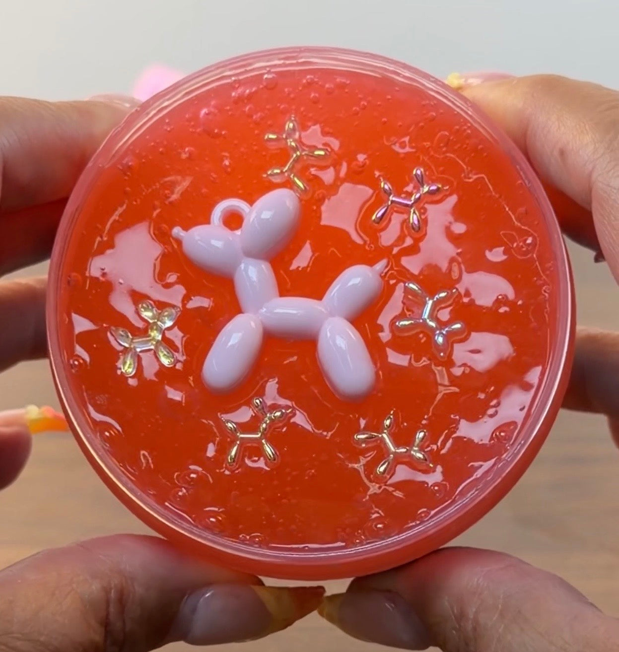 red coated clear slime with a plastic balloon dog charm with plastic balloon dog sprinkles