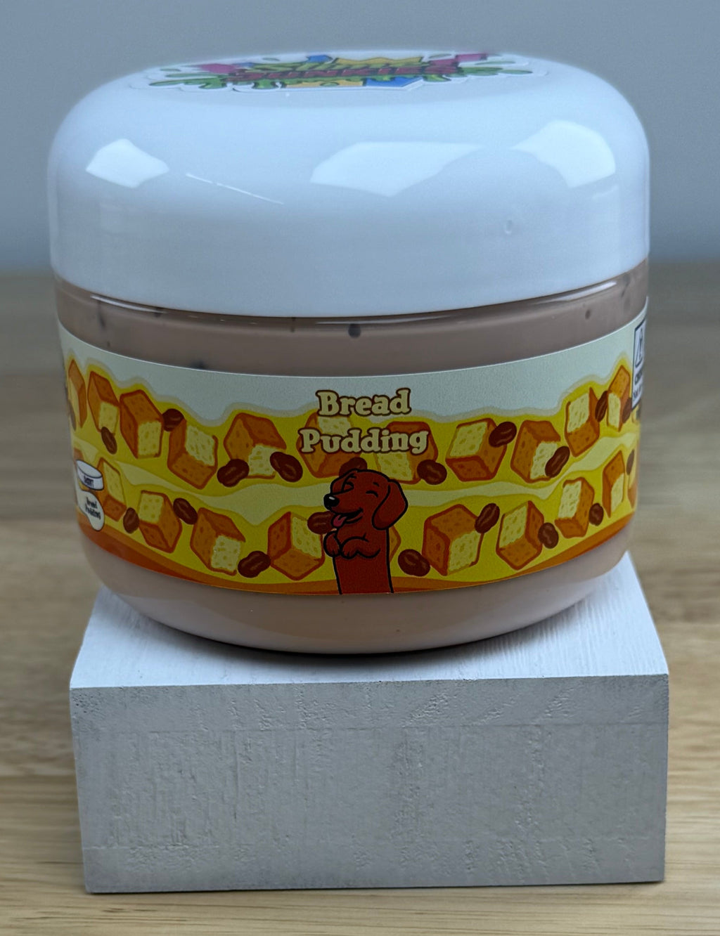 bread pudding tan slime with dark brown pebbles in a clear jar with a bread pudding label with bread raisins and a dog