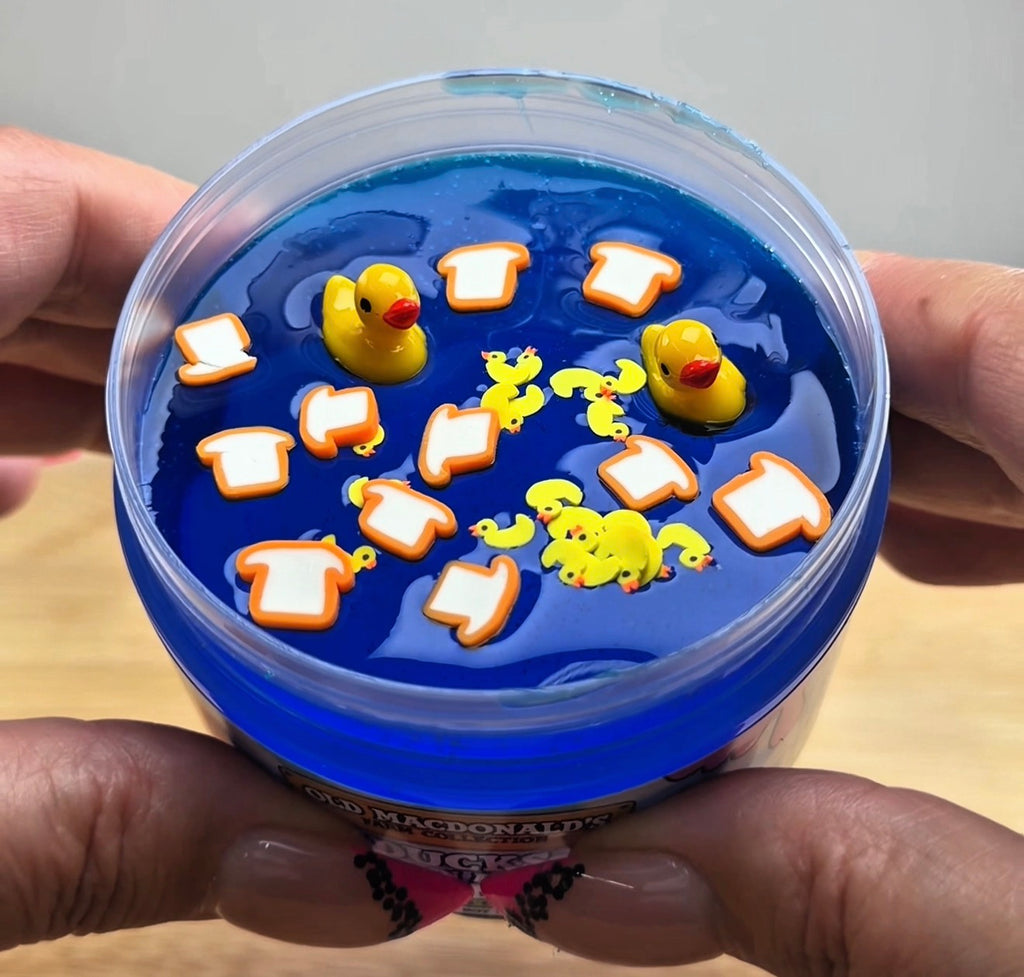 clear blue slime with ducks and bread clay slices in a clear jar with an old macdonald's farm collection ducks on a pond label with a farm background and duck