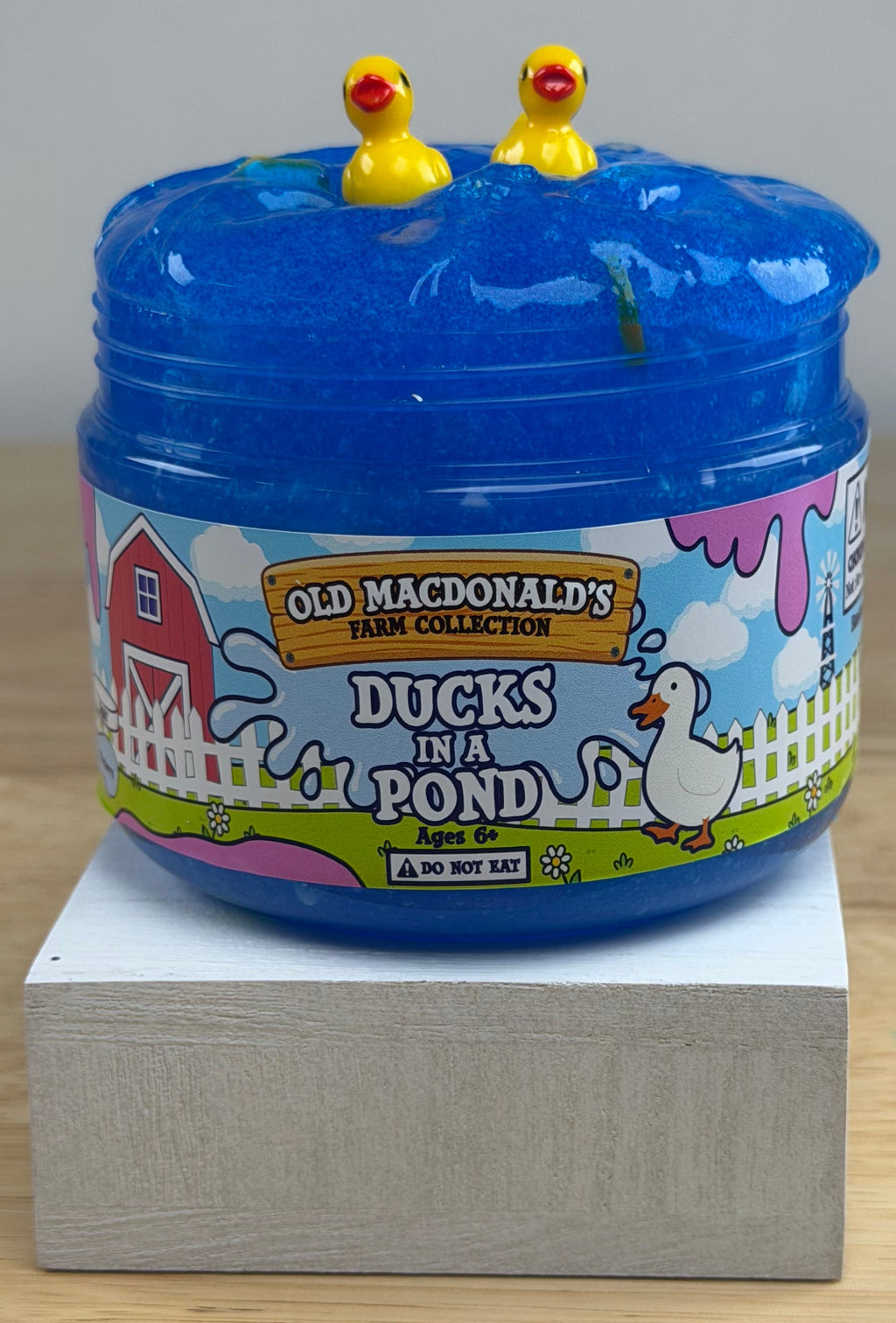 clear blue slime with ducks and bread clay slices in a clear jar with an old macdonald's farm collection ducks on a pond label with a farm background and duck