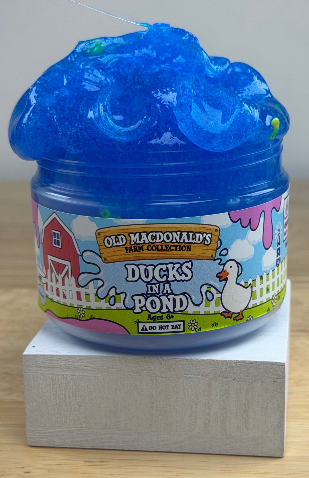 clear blue slime with ducks and bread clay slices in a clear jar with an old macdonald's farm collection ducks on a pond label with a farm background and duck