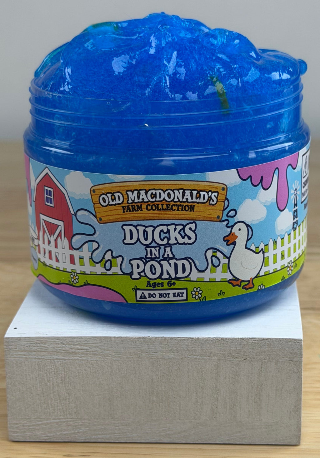 clear blue slime with ducks and bread clay slices in a clear jar with an old macdonald's farm collection ducks on a pond label with a farm background and duck