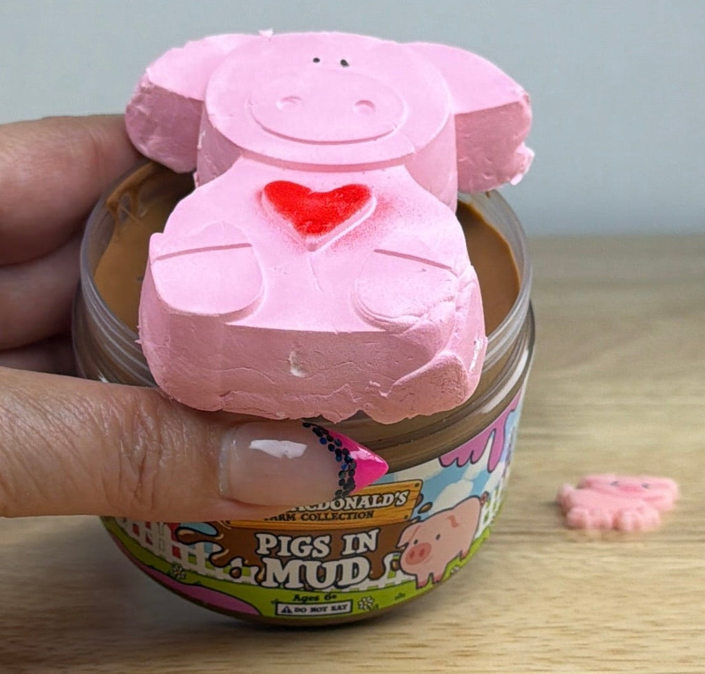 brown slime with a pig clay piece in a clear jar with an old macdonald farm collection farm label with a pig on it