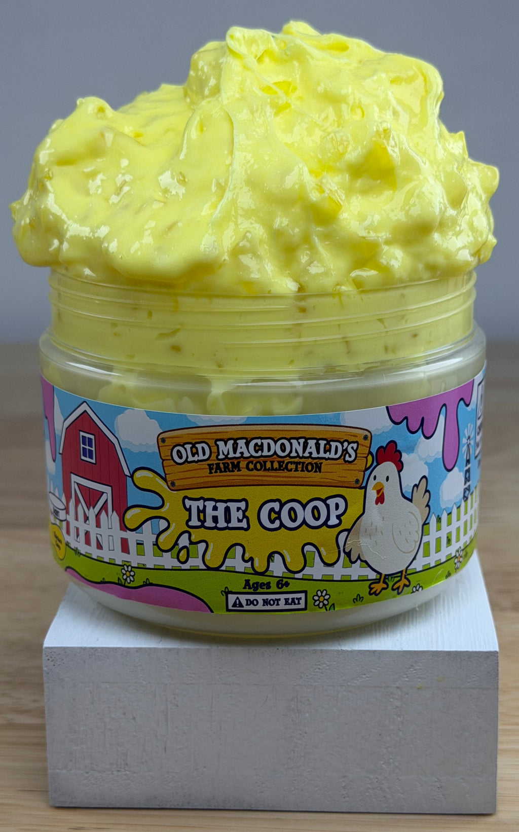 yellow slime with silica in a clear jar with a farm label that says old macdonald's farm collection the coop with a chicken topped with a chicken basket two eggs and a baby chicken