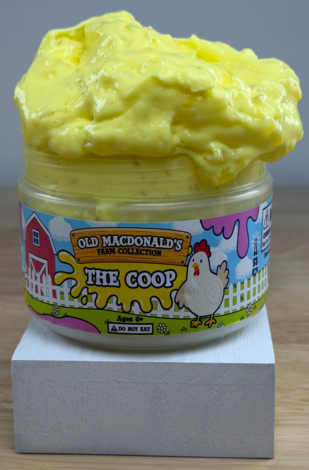 yellow slime with silica in a clear jar with a farm label that says old macdonald's farm collection the coop with a chicken topped with a chicken basket two eggs and a baby chicken