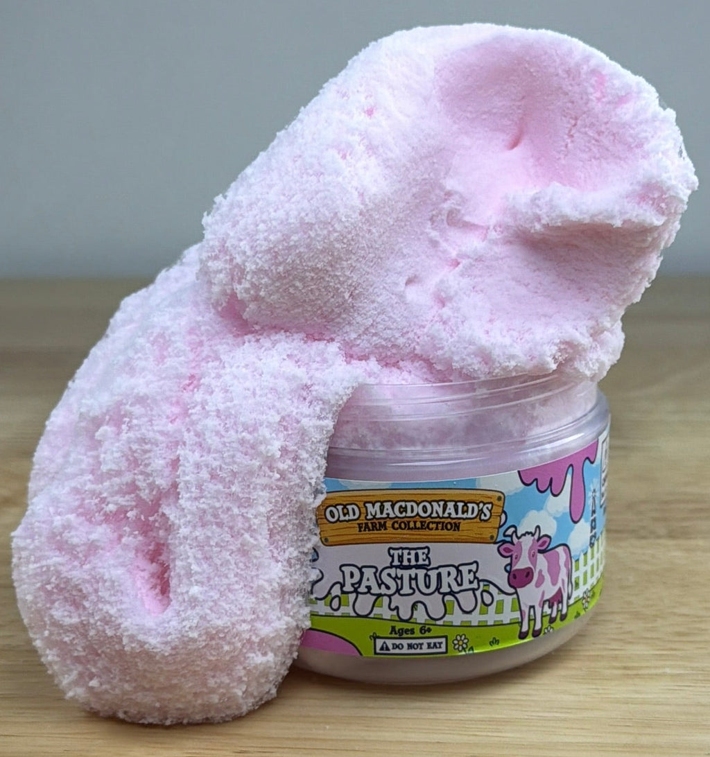 white and pink cloud slime with a cow charm in a clear jar with an old macdonald farm label with a cow that says the pasture