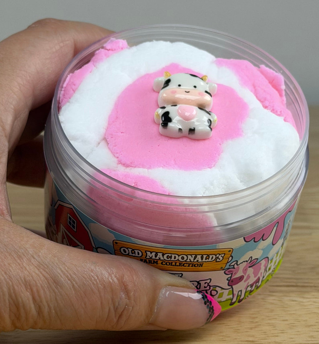 white and pink cloud slime with a cow charm in a clear jar with an old macdonald farm label with a cow that says the pasture
