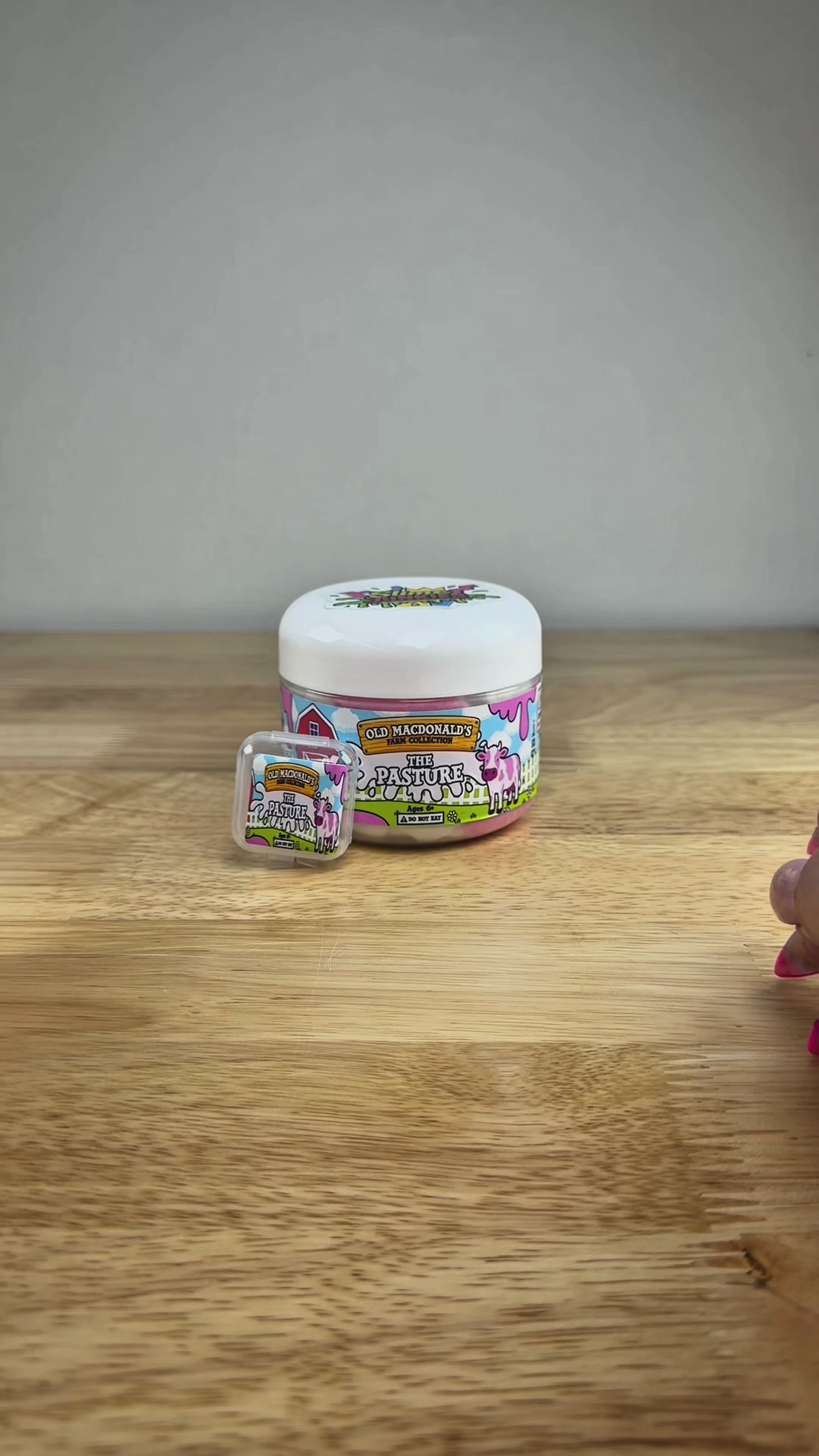 white and pink cloud slime with a cow charm in a clear jar with an old macdonald farm label with a cow that says the pasture