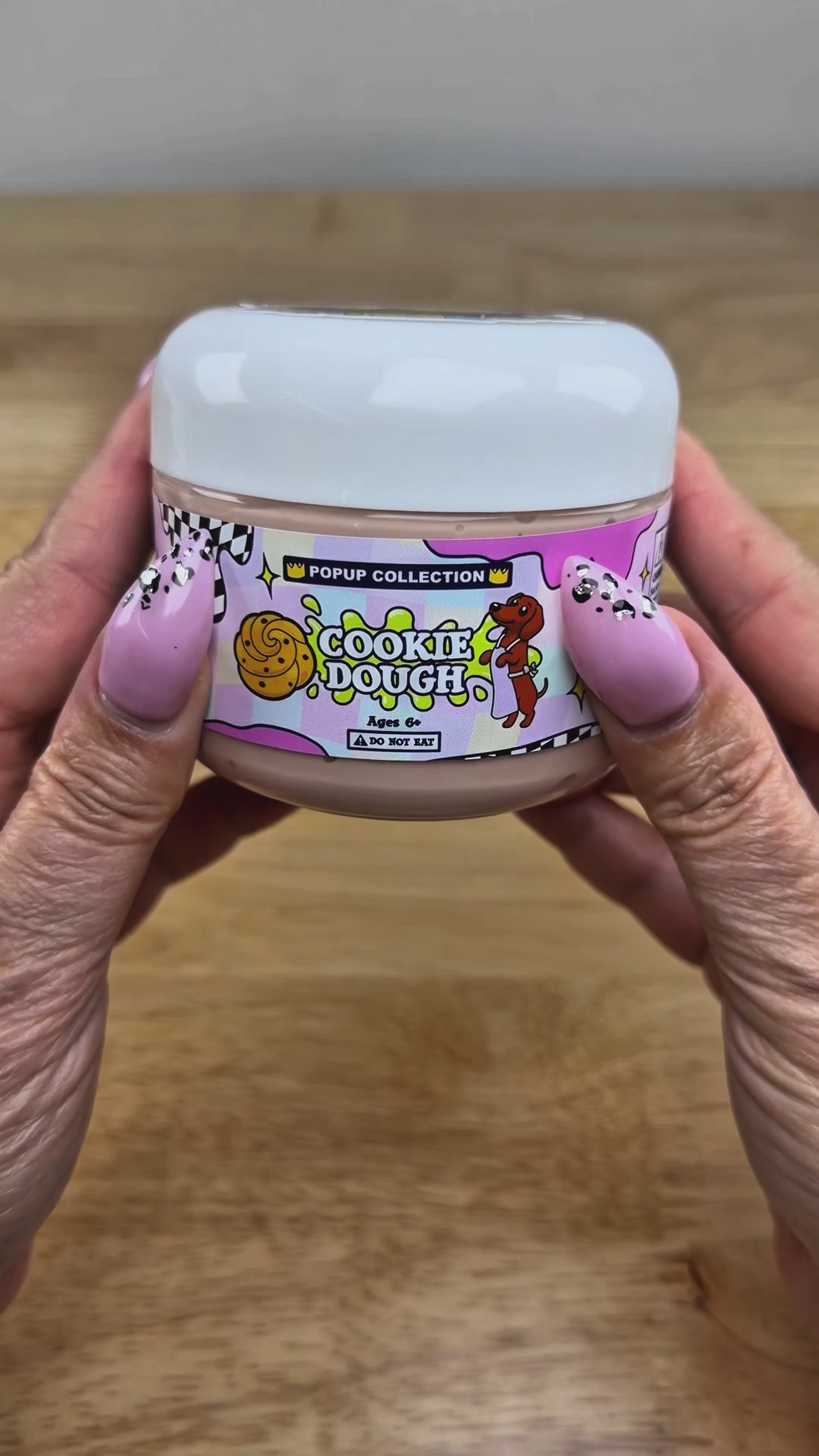 Light tan thick and glossy slime in a plastic jar labelled pop up collection with a dog and a cookie dough logo labelled cookie dough